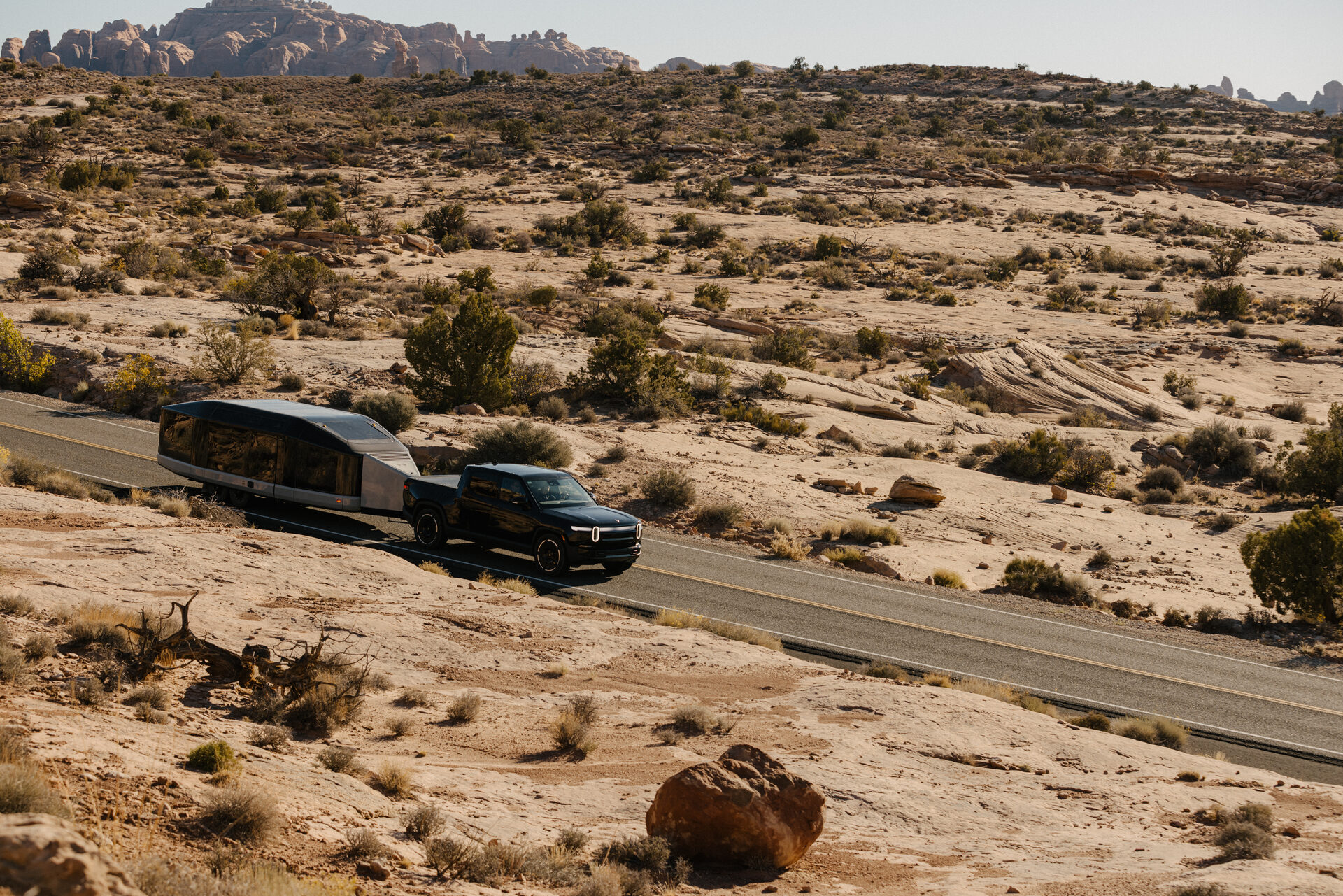 A Rivian towing the Lightship AE1 in road mode down an open highway